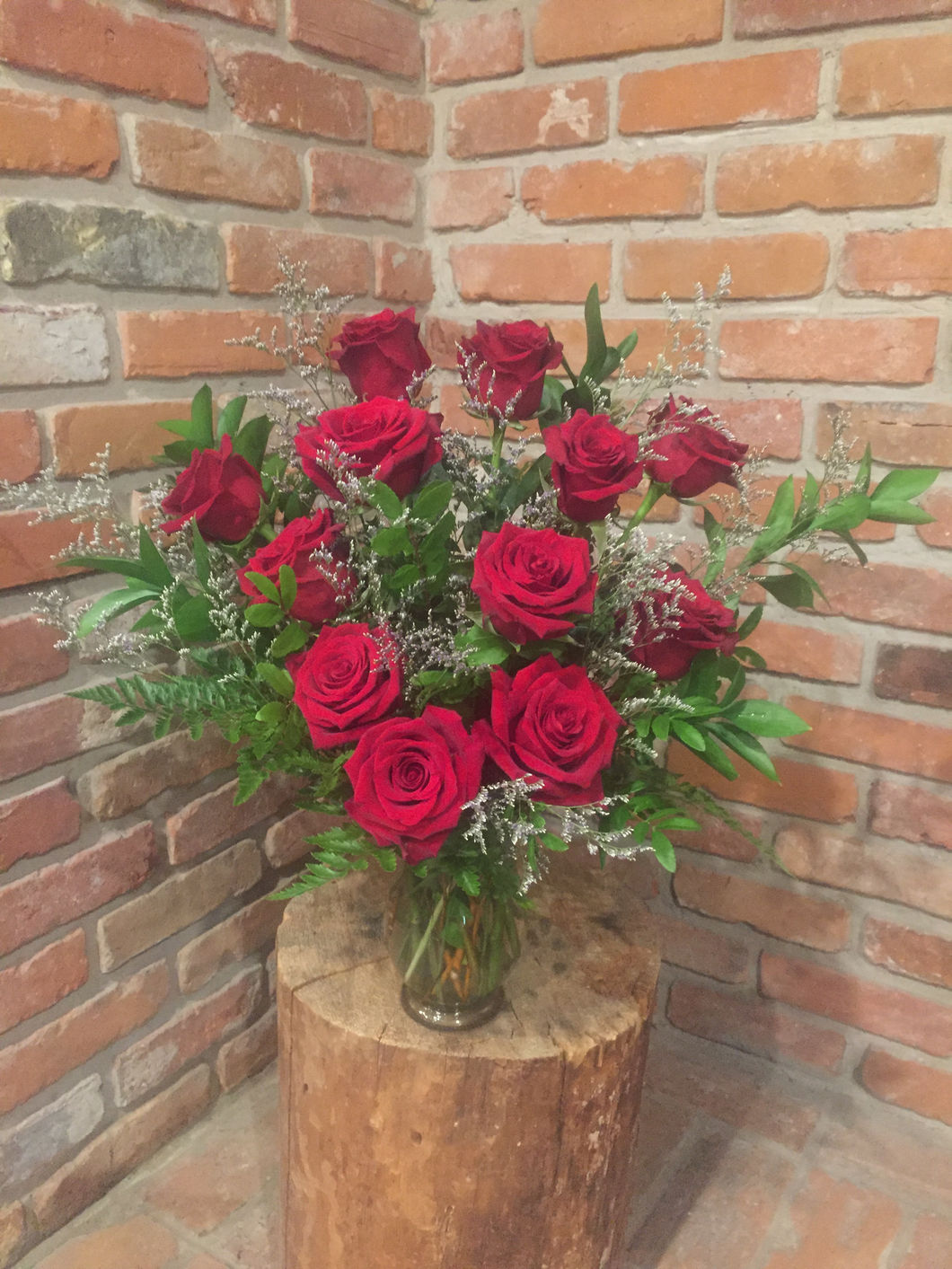 A vase arrangement of a dozen of our premium Explorer Red Roses with an assortment of foliages and whispy lavender limonium for a touch of romance