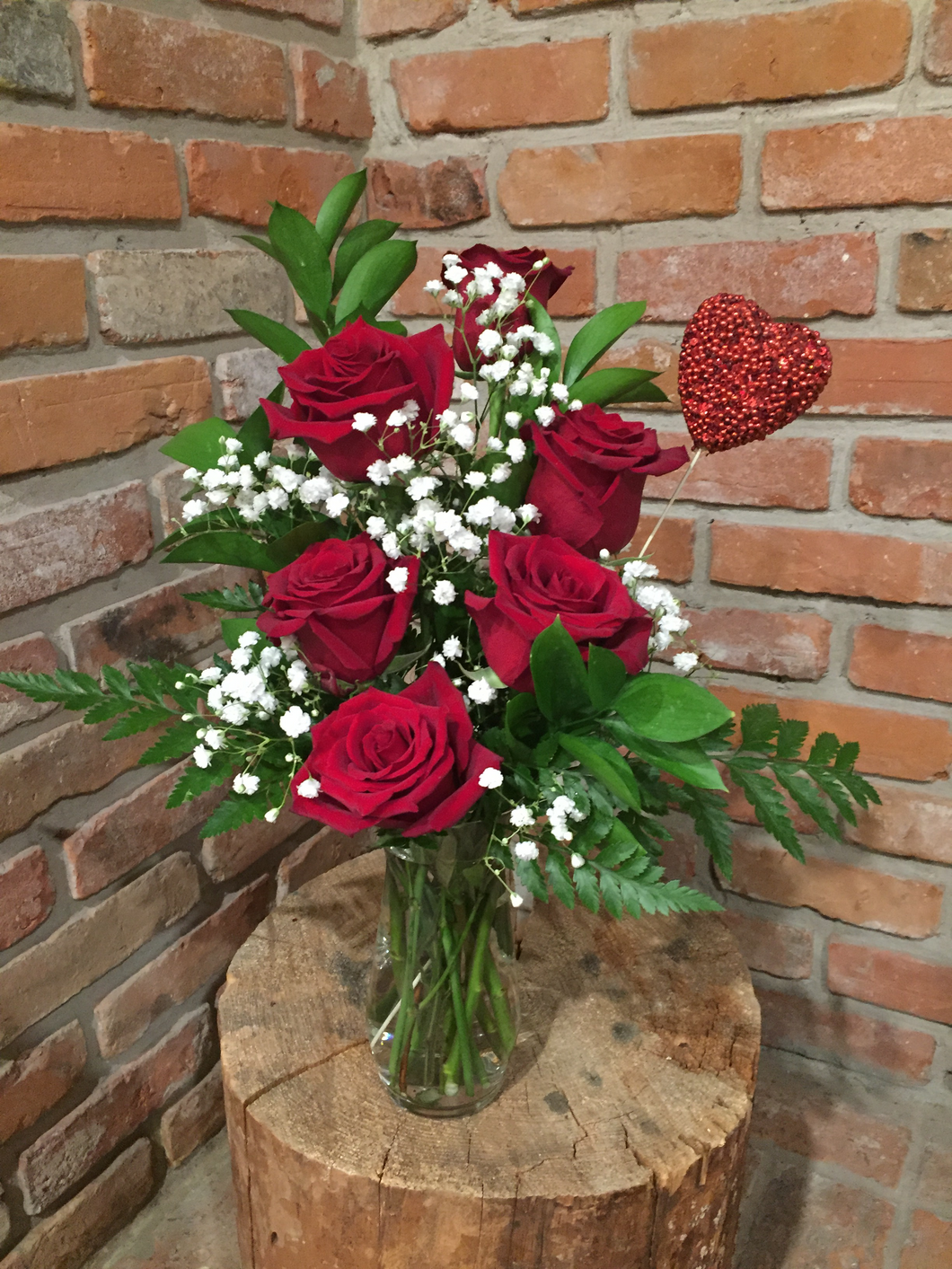 A vase arrangement of a half dozen of our premium Explorer Red Roses with babies breath and an assortment of foliages finished with a heart accent
