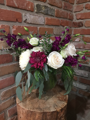 Soft green eucalyptus drapes over a clear glass vase. Deep purple stocks and creamy Playa Blanca roses are the stars of this garden style arrangement  complemented by long lasting cremons and lisianthus   Available for delivery in Kenora