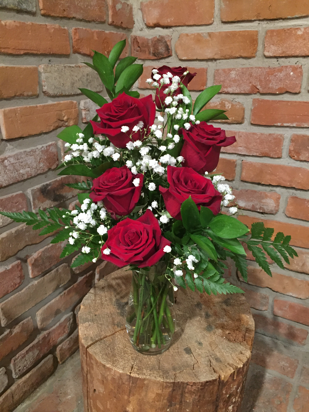 A vase arrangement of a half dozen of our premium Explorer Red Roses with fragrant white babies breath and an assortment of foliages 